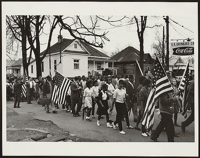[Participants, some carrying American flags, marching in the civil rights march from Selma to Montgomery, Alabama in 1965]