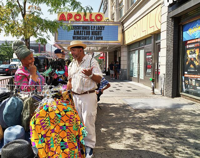 Stanley Guy, a New York actor, looks over shirts for sale outside the famous Apollo Theater in the Harlem neighborhood of upper Manhattan borough, one of five such county-like political jurisdictions in sprawling New York City